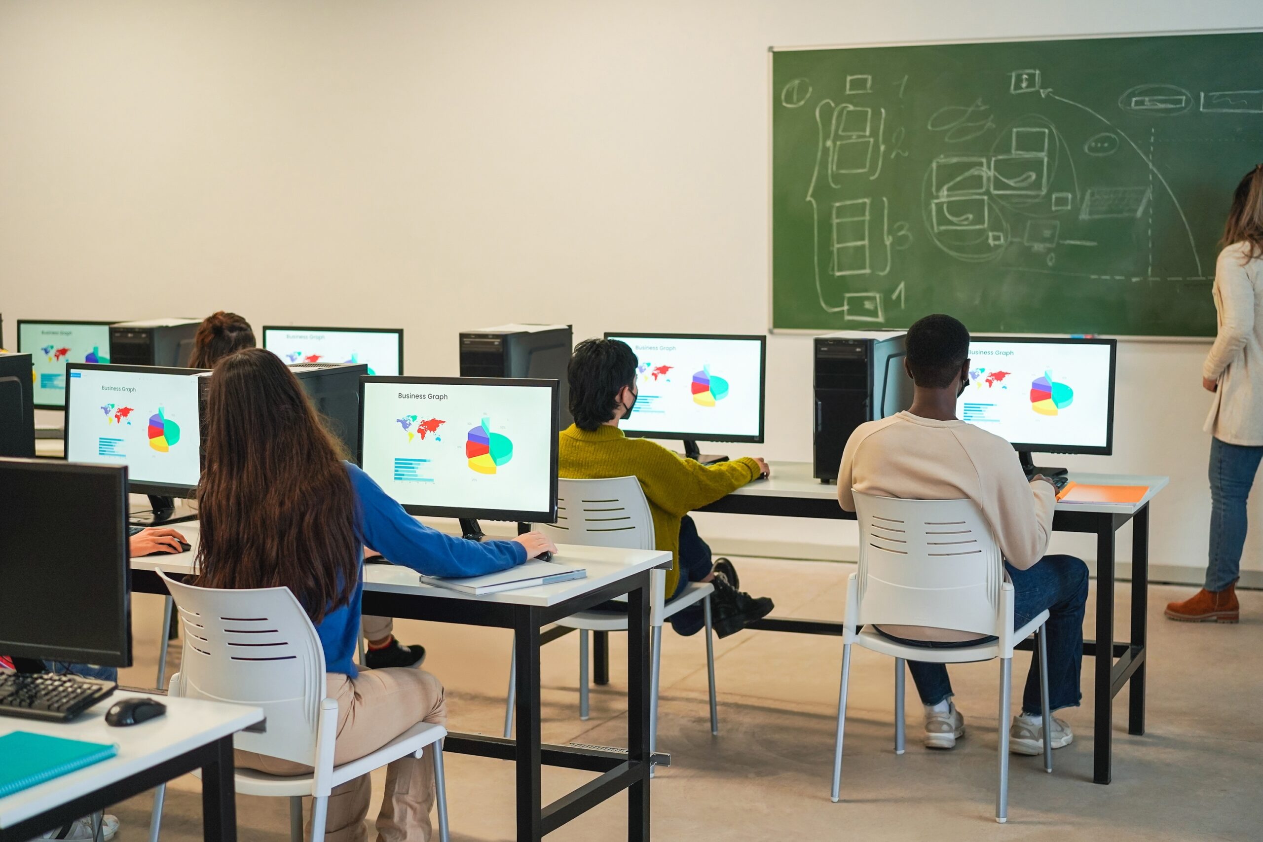 Estudiantes en aula de informática aprendiendo con ordenadores en formación profesional dual.