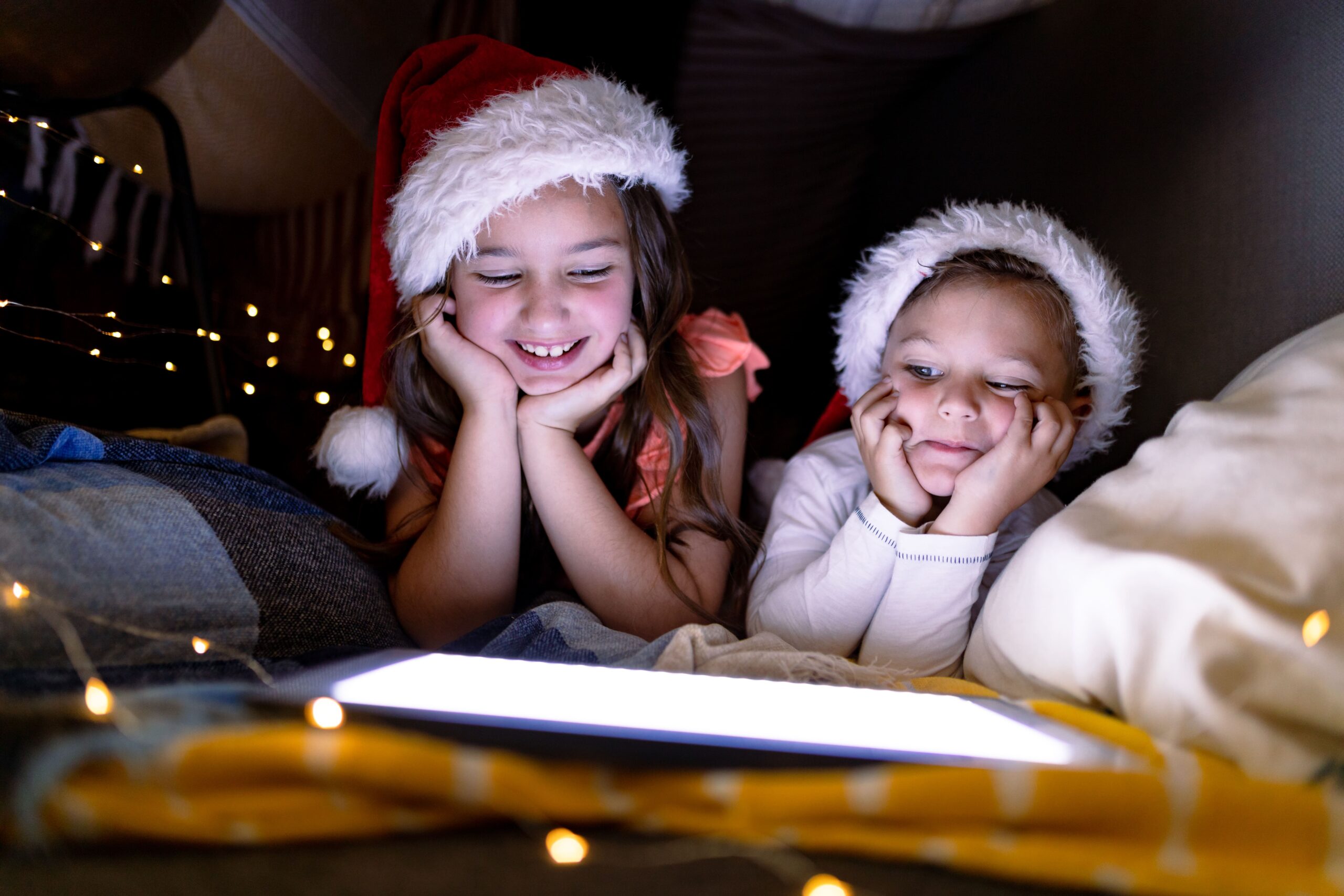 Niños leyendo una historia navideña antes de dormir, compartiendo un momento de lectura familiar que educa en valores durante la Navidad.